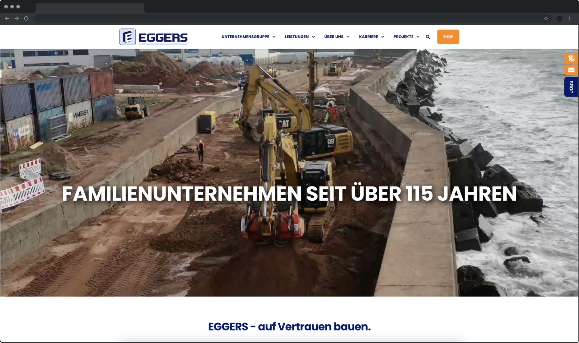 Bauarbeiter nutzen schwere Maschinen, um eine Küstenschutzmauer an einem Hafen zu errichten.