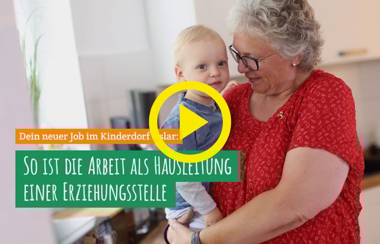 Ältere Frau hält Kleinkind im Arm, Text: 'Dein neuer Job im Kinderdorf Uslar: So ist die Arbeit als Hausleitung einer Erziehungsstelle', gelbes Play-Symbol.